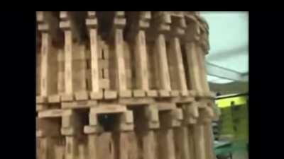 Reporter knocks down jenga tower with wired microphone.