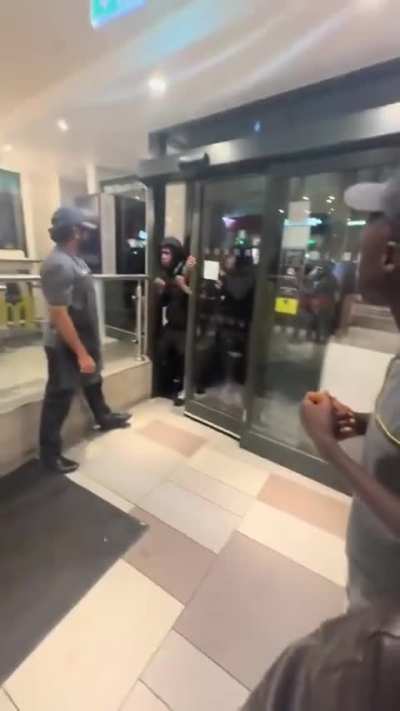 Group of people forcing their way into a McDonald's in Dalston, London.