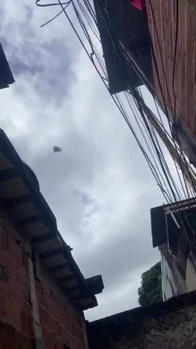 This guy flying a kite while sitting in a wall-surrounded narrow space