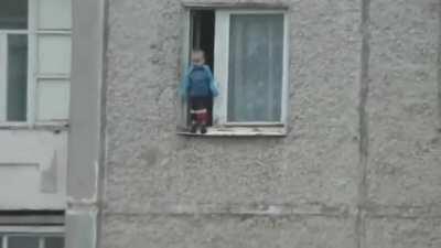 Child enjoys the view from his apartment window