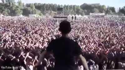 A band’s lighting technician signals to his colleague as he tests the stage set-up - and the crowd copies him.