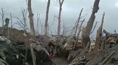 A Group of Russian soldiers firing from a trench, one of them is hit in the helmet