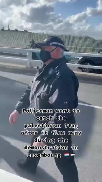 Policeman brings back a Palestinian flag that flew away during a demonstration in Luxembourg
