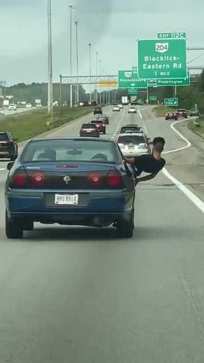 Kid leans out the window on the freeway.