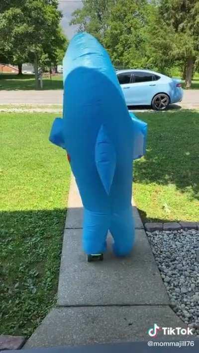 Mother filming daughter trying to longboard in crocs & a shark suit