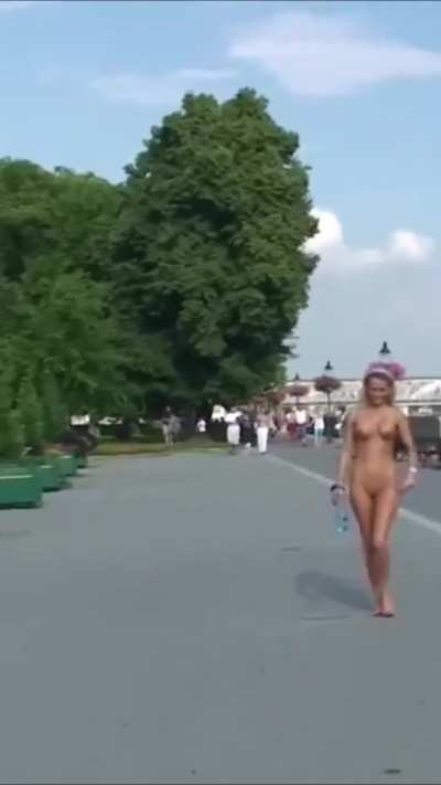 A naked blonde strolls along the embankment