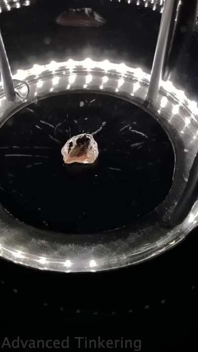 A piece of Uranium ore emitting radiation inside a cloud chamber.