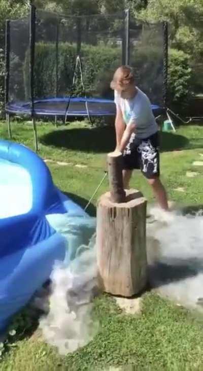 Boy tries to cut an apple with a sword beside a pool