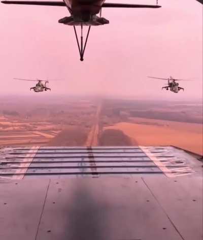 Two Mi-24s are flying behind a Mi-17V-5
