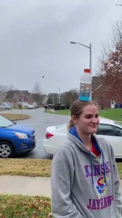 Posing as a bottle stand for a football trick-shot