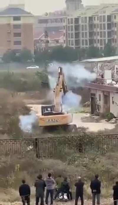 Somewhere in China some person uses fireworks to fight off bulldozer sent to demolish his building