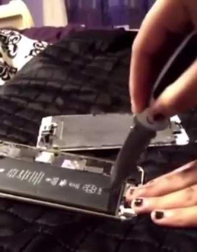 Opening a phone batery with a knife in a bed.