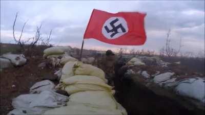 Azov Battalion in Ukraine firing some sort of LMG with a waving Nazi flag.