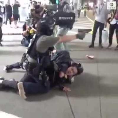 Officer puts subdued protester in chokehold while other points gun at bystanders