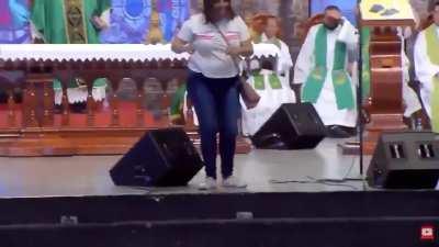 Woman pushes Brazilian priest off the stage during a live broadcast