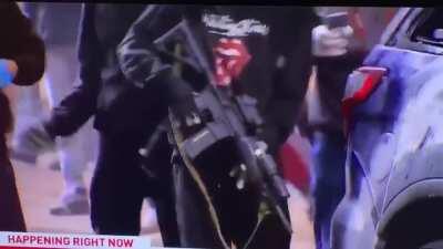 Rioter pulls AR-15 from cop car, gets stopped immediately by private security officer for news team