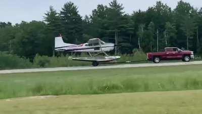 A float plane taking off from a trailer being towed by a truck