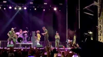Brass Against lead singer urinates on fans face in middle of show on stage, while on jumbo screen, in front of the whole audience.