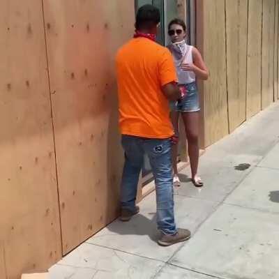 Woman stopped someone from boarding up a store in Santa Monica, CA so she could hold the drill for a picture, then drove away.
