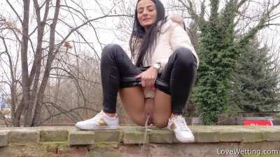 Silvia Black pees off the wall by the road as vehicles drive by