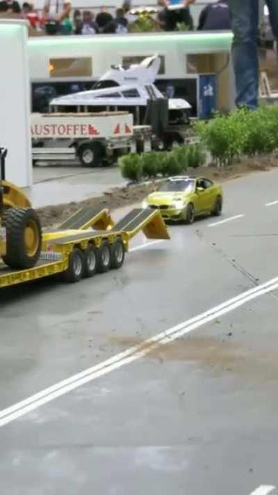 A remote control car, driving onto a retractable ramp on a remote control truck.