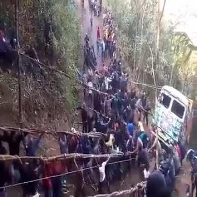 Large group of people pulling a truck up hill after it broke down