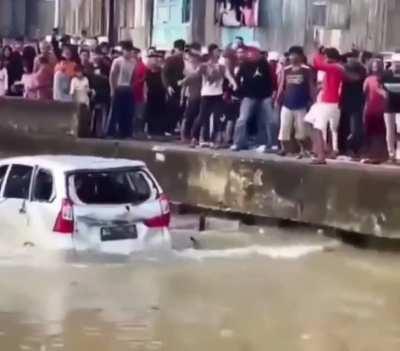 Angry villagers push a Toyota Avanza into river after driver allegedly hit another villager.