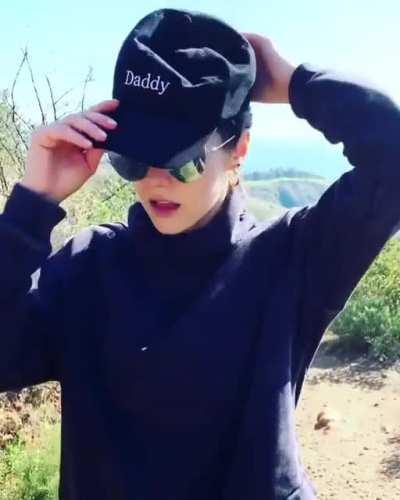 tying her hair, then puts on the Daddy cap