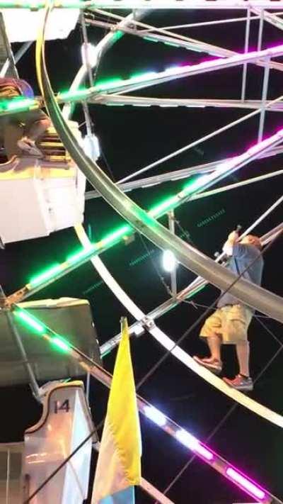 Carnival worker climbs and falls while fixing stuck Ferris wheel car to save kids
