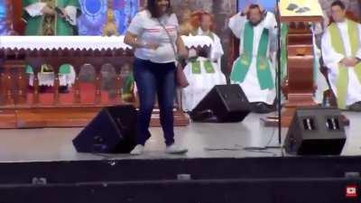 Woman violently pushes Priest off stage during mass live broadcast.