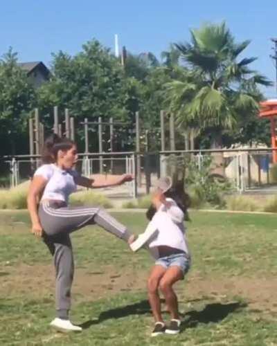 Attempting to kick a cup off her friends head