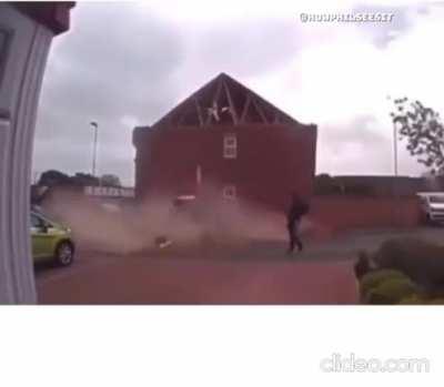 man casual walks away right after a roof wall fall's inch's away from him