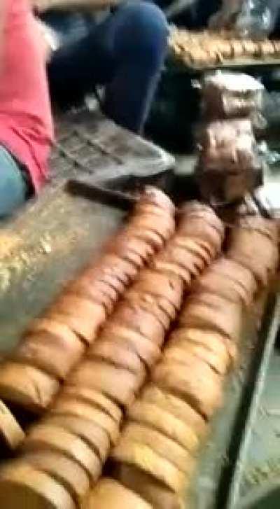 Workers at a bakery licking and stamping the food as they pack it to sell them.