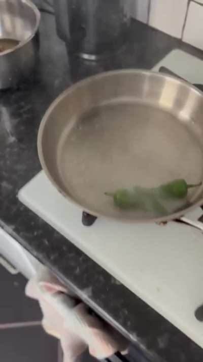 Putting wet chillies in a scotching hot pan while recording a cooking video