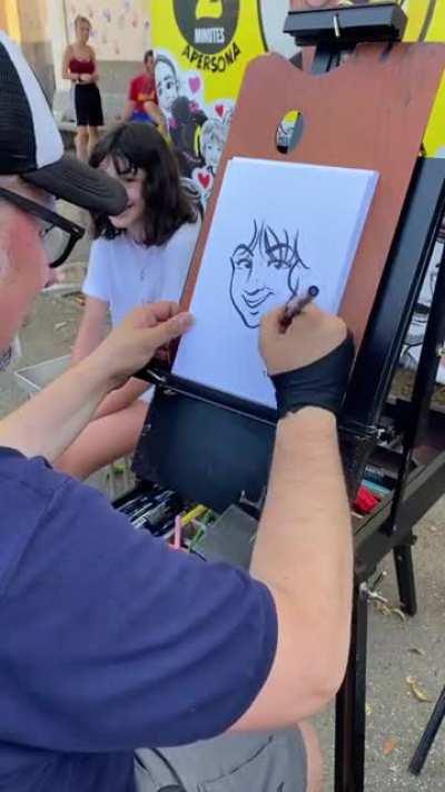 A street artist draws cartoon version of a girl