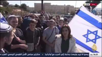 Crowd of Israeli colonists heard Aljazeera reporter speaking Arabic to the camera so they attempted to disrupt the live report by blocking the camera and shouting things like 