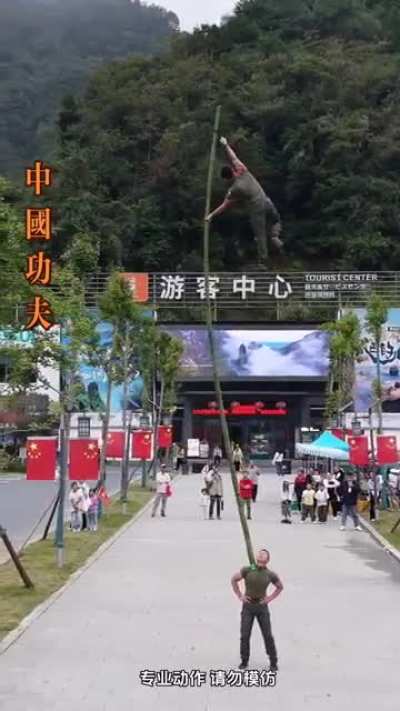Chinese Kung-fu Acrobats demonstrate Balancing act on a Bamboo in front of a tourist center.