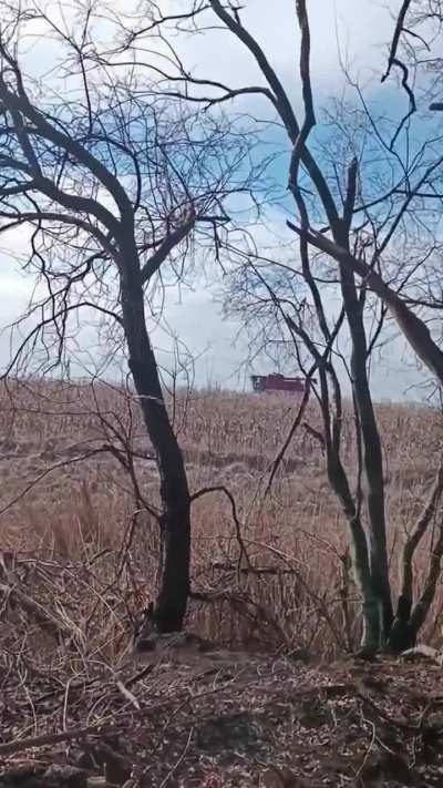 Ukrainian artillery firing from a dugout, while a farmer drives his combine in the field right next to them.