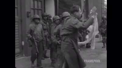American soldiers watch as a Jewish concentration camp inmate beats up the Nazi guard who held him at Dachau, 1945