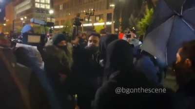 Man demanding peace is surrounded by Antifa and obscured by their umbrellas/shields, pushed back into mob when he tries to escape