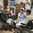 Nurse helps elders to play ping pong.